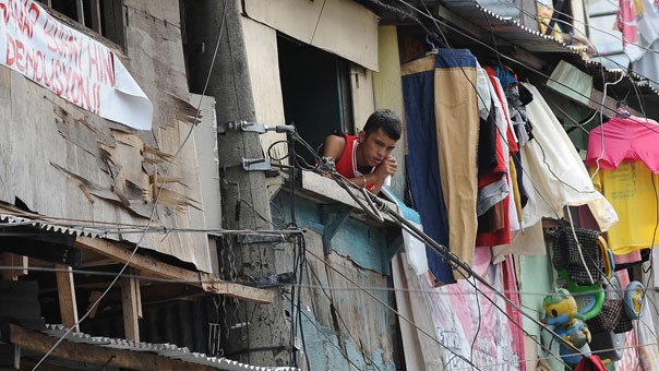 Một người đàn ông nhìn ra cửa sổ của ngôi nhà tạm tại Manila.