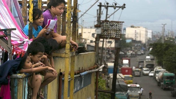 Những đứa trẻ đang nhìn xuống thành phố Manila từ một tòa nhà chung cư cao tầng đông đúc trong các khu ổ chuột ở quận Tondo. Do tình trạng quá tải, người dân buộc phải sống thậm chí ở các khu định cư tạm dưới gầm cầu, dọc theo các tuyến đường sắt và thậm chí cả trong nghĩa trang.