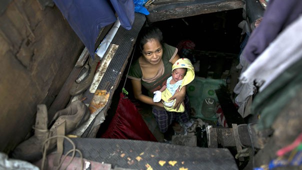 Irish Romes bế con trai mới sinh của mình, Jay, bên trong một chỗ ở chật hẹp sống với gia đình bên cạnh một đường cao tốc ở Binondo.