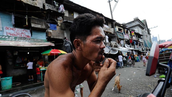 Một người đàn ông đang cạo râu trong khu ổ chuột ở Manila.