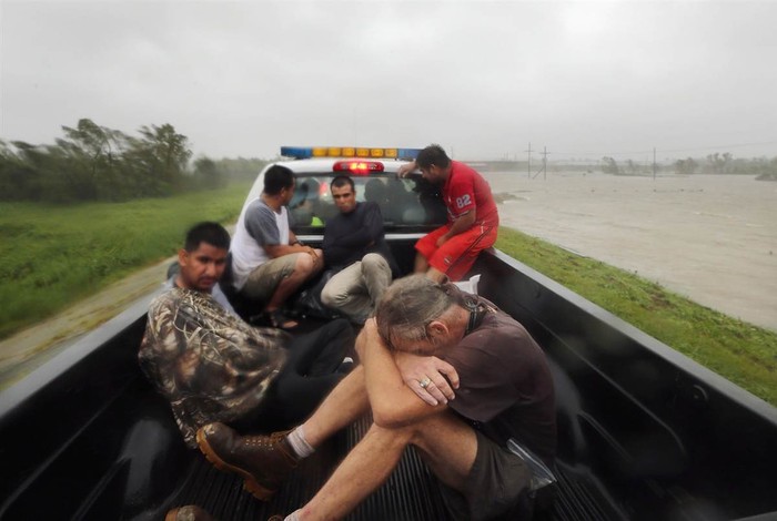 Người dân nghỉ ngơi trên một chiếc xe tải cứu hộ trên đỉnh một con đê bên cạnh dòng nước lũ chảy siết sau khi được cứu ở Plaquemines Parish,bang Louisiana, Mỹ hôm 29/8. Hàng chục người đã được cứu sống trong khu vực này đúng vào ngày kỷ niệm 7 năm cơn bão Katrina kinh hoàng ập đến.