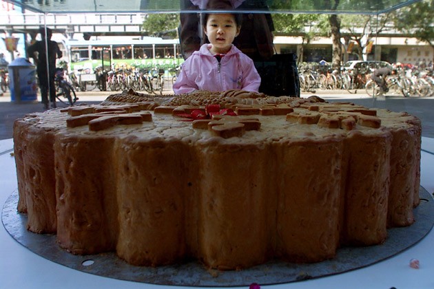 Một bé gái Trung Quốc chăm chăm nhìn chiếc bánh trung thu khổng lồ bên ngoài một trung tâm mua sắm ở Bắc Kinh.