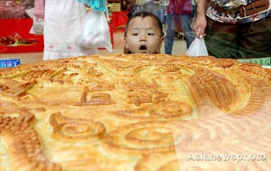 Một đứa trẻ tỏ vẻ đầy ngạc nhiên trước chiếc bánh trung thu nặng tới 75,5 kg tại một cửa hàng ở Hứa Xương, tỉnh Hà Nam, Trung Quốc vào ngày 1/9/2011.