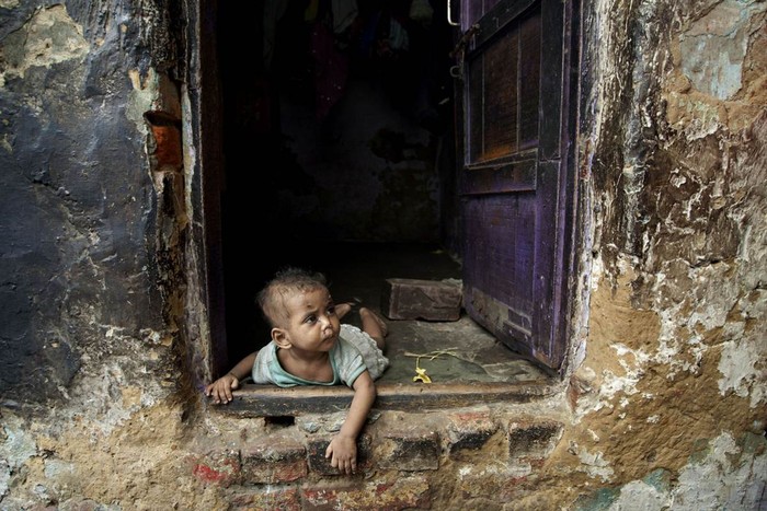 Một em bé đang bò ra gần cửa nhà mình trong một khu phố ổ chuột ở New Delhi, Ấn Độ. Một báo cáo của 3 cơ quan Liên Hiệp Quốc và Ngân hàng Thế giới cho biết, tỷ lệ tử vong trẻ em trên toàn thế giới đã giảm 41% kể từ năm 1990 và khoảng một nửa trong số trẻ em tử vong chỉ xảy ra trong năm quốc gia, bao gồm Ấn Độ.