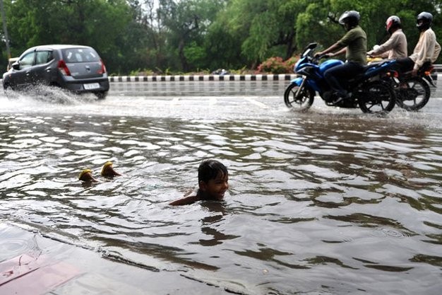 Một cậu bé bơi giữa đường phố sau cơn mưa lớn ở New Delhi.