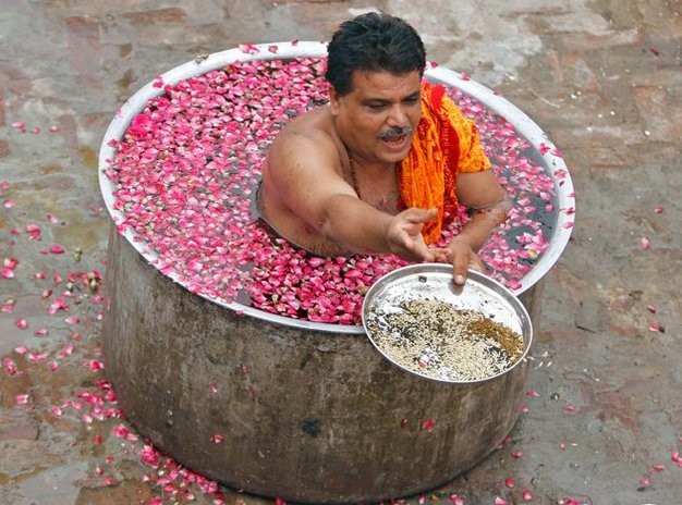 Ở thành phố Ahmedabad, một giáo sĩ Hindu ngồi trong một chiếc nồi lớn chứa đầy nước và cánh hoa, để cầu nguyện trong buổi lễ cầu mưa.