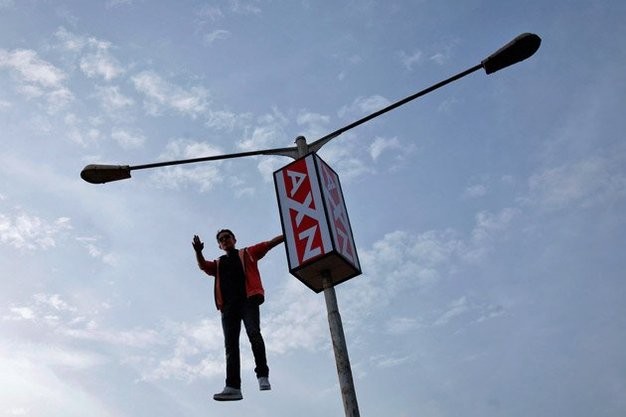 Ảo thuật gia Cyril Takayama treo người trên một cột đèn đường tại Mumbai.
