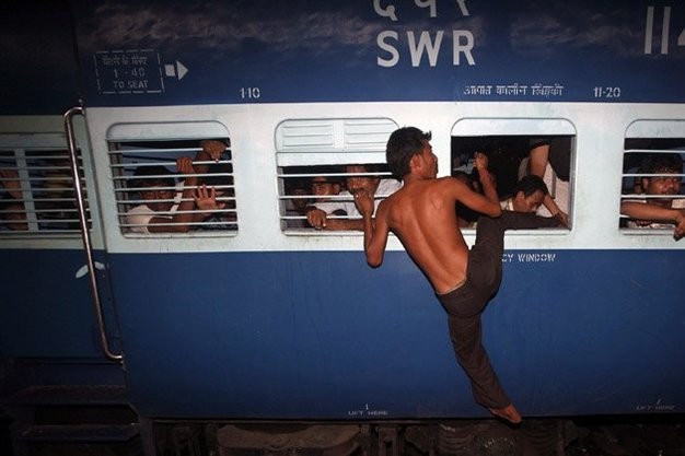 Một người đàn ông đang cố gắng leo lên thành cửa sổ ở ga xe lửa Calcutta.