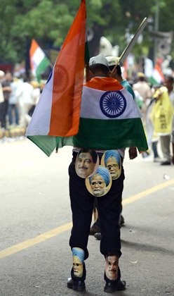 Một người biểu tình là thành viên của tổ chức chống tham nhũng dán hình Thủ tướng Ấn Độ Manmohan Singh và lãnh đạo đảng Bharatiya Janata.
