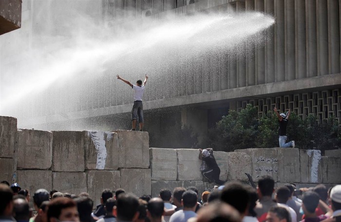 Lực lượng an ninh Ai Cập sử dụng vòi rồng để giải tán đám đông biểu tình. Một số người còn trèo lên những khối xi măng được sử dụng để chặn con đường dẫn đến Đại sứ quán Mỹ, trong cuộc đụng độ tại Cairo, Ai Cập.