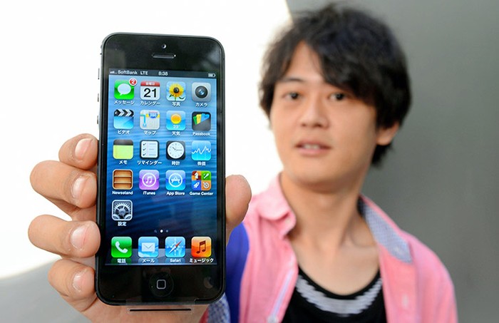 Một người đàn ông khoe chiếc iPhone 5 của mình sau khi xếp hàng cả đêm để mua nó.