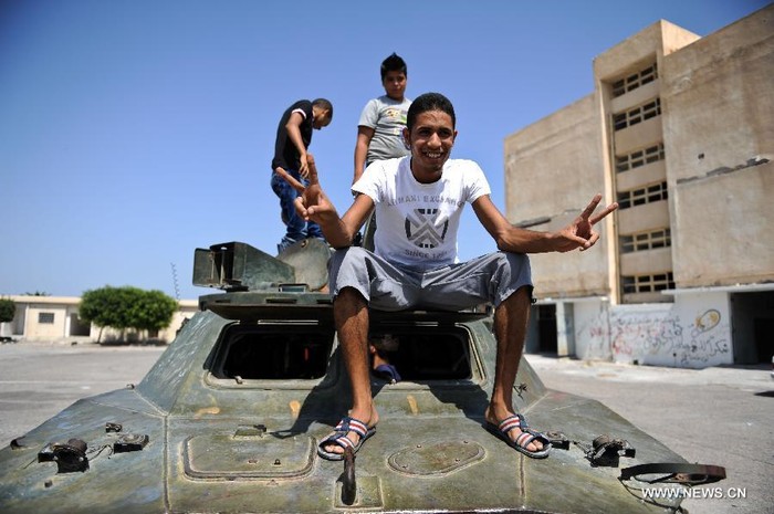 Một thanh niên Libya chụp ảnh bên một xe bọc thép bị bỏ lại ở Bab Al-azizia, Tripoli,
