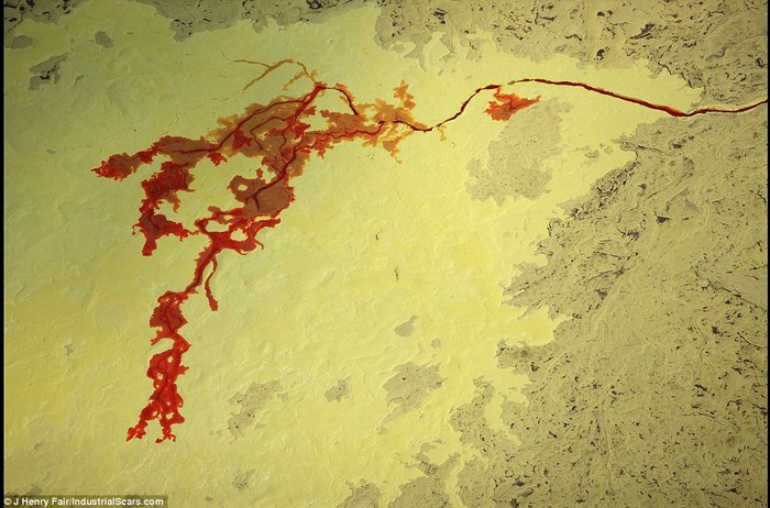 Quá trình chiết xuất dầu từ cát đã để lại những vùng lưu huỳnh màu vàng rộng lớn. Trong bức ảnh này là một khu lưu trữ lưu huỳnh nằm gần một con sông ô nhiễm đã biến thành màu đỏ tại Fort McMurray,