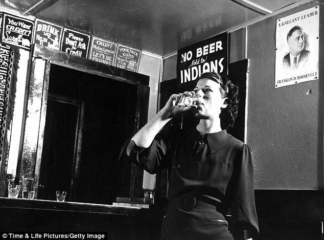 Một phụ nữ đang uống rượu làm nổi bật lên các tấm áp phích tuyên truyền phân biệt đối với của những người Mỹ bản địa trong năm 1936 và một tấm chân dung của Tổng thống Franklin Delano Roosevelt