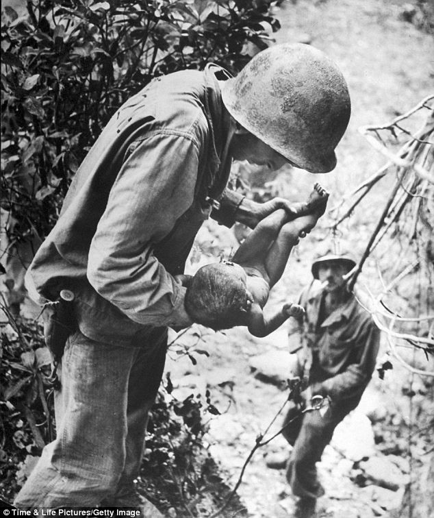 Một lính Mỹ đang bế một em bé sơ sinh gần chết mà anh tìm thấy bị bỏ rơi bên dưới một tảng đá gần một hang động ở Nhật Bản trong Thế chiến II