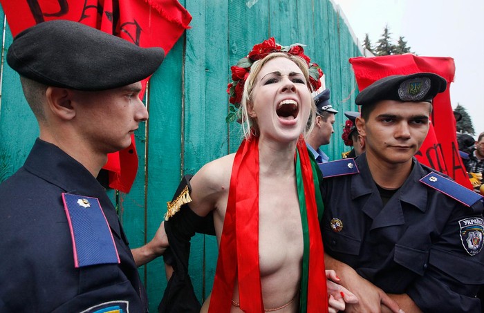 Cảnh sát bắt giữ một thành viên của FEMEN trước Quốc hội Ucraina phản đối cải cách quỹ lương hưu trong đó dự kiến sẽ nâng cao độ tuổi nghỉ hưu của phụ nữ