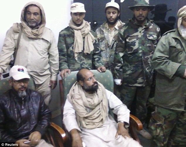 Saif (áo trắng, ngồi) vừa mới bị bắt giữ ở Libya sau nhiều tuần chạy trốn