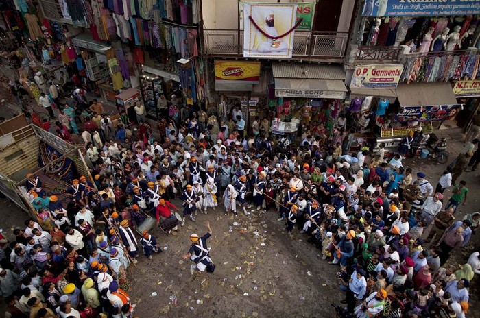 Một đám đông người Sikh ở Ấn Độ đang vây quanh các nghệ sĩ biểu diễn võ thuật trong một đám rước tôn giáo tại New Delhi hôm 24/11. Đám rước được tổ chức để đánh dấu sự tử vì đạo của Guru Tegh Bahadur, một người Sikh qua đời ở New Delhi năm 1675.