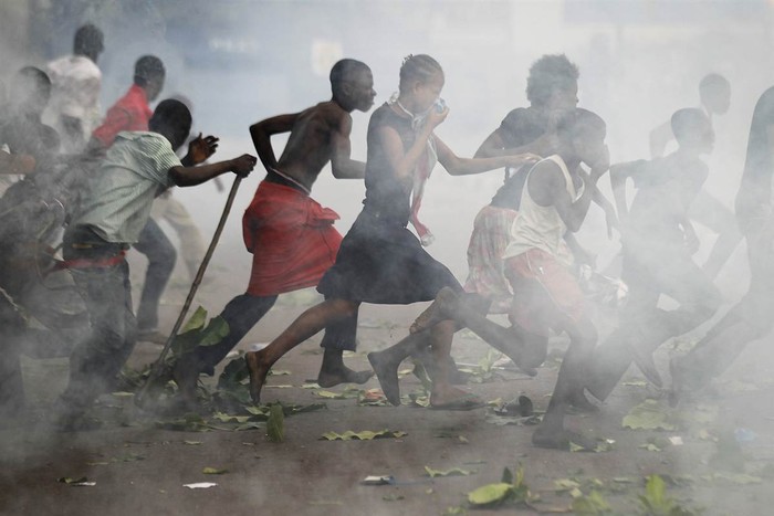 Những người ủng hộ Liên minh Dân chủ và tiến bộ xã hội đang chạy qua một đám khói hơi cay bên ngoài sân bay N'Djili ở Kinshasa, Congo ngày 26/11.