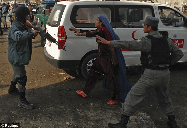 Cảnh sát Afghanistan đang cố ngăn một phụ nữ đòi vào bên trong hiện trường vụ nổ tìm kiếm người thân