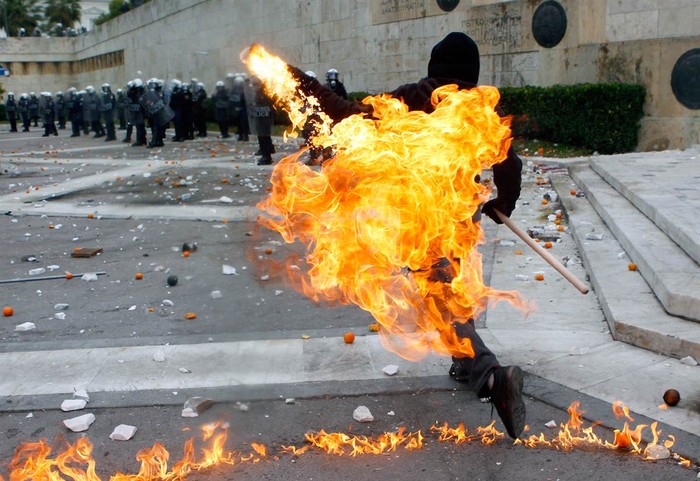 Một người biểu tình ném bom xăng vào cảnh sát chống bạo động đang bảo vệ tòa nhà Quốc hội tại quảng trường Syntagma của Athens trong cuộc đụng độ hôm 6/12