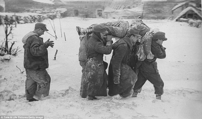 Các tù binh Đức mang thi thể người lính Mỹ đã hy sinh trong trận "Battle of Bulge" băng qua rừng Ardennes đầy tuyết.