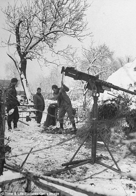 Lính Mỹ đào đất bên cạnh một khẩu súng máy trong trận "Battle of Bulge"