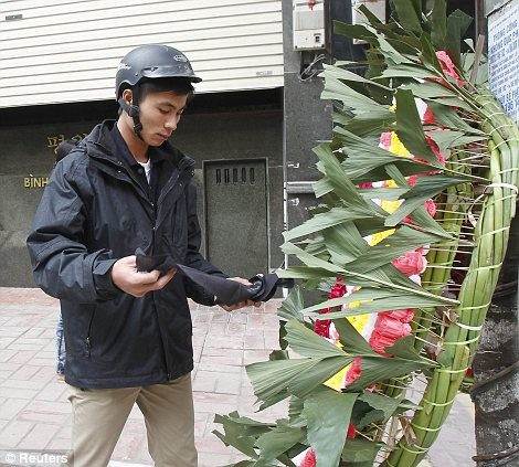 Một thanh niên đặt vòng hoa tưởng niệm Chủ tịch Kim Jong Il trước cửa một nhà hàng Bình Nhưỡng tại Hà Nội, Việt Nam