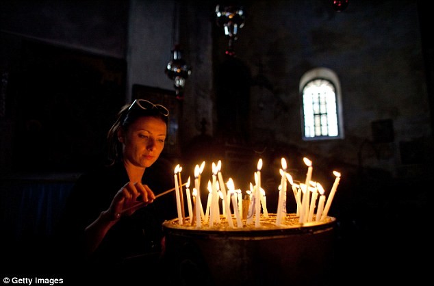 Một người phụ nữ thắp nến trước khi tham gia cầu nguyện trong đêm lễ Giáng sinh