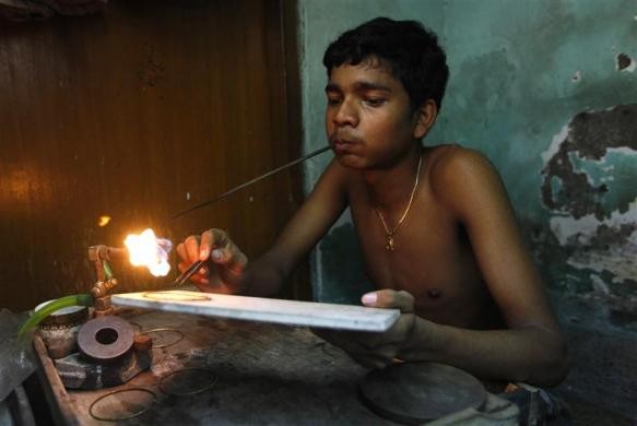 Một thợ kim hoàn nhỏ tuổi đang chế tác chiếc lắc tay ở cửa hàng tại Kolkata ngày 1/8/2011