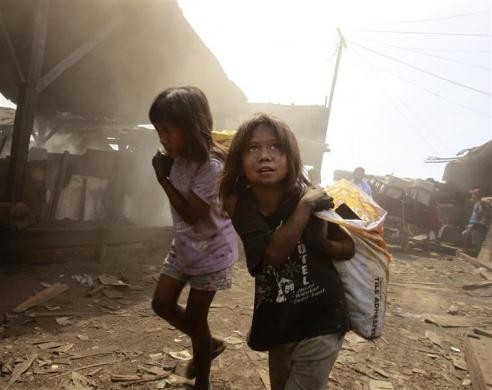 Các bé gái vác những chiếc bao tải tại nhà máy than ở khu ổ chuột ở Manila, Philippines ngày 12/4/2011
