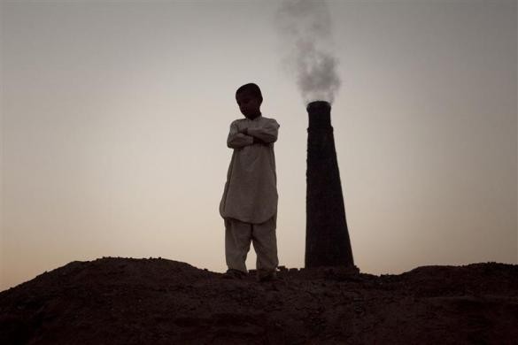 Ahsan, 12 tuổi, đứng trước ống khói của một nhà máy gạch ở Islamabad, Pakistan ngày 23/11/2010