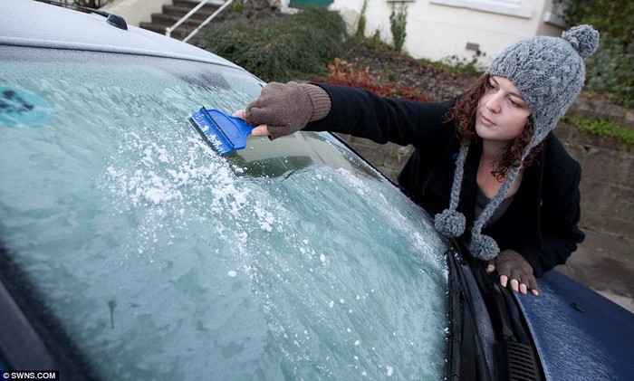 Ellie Connolly, 27 tuổi, đang làm sạch lớp sương giá phủ trên kính xe hơi tại Plymouth, Devon