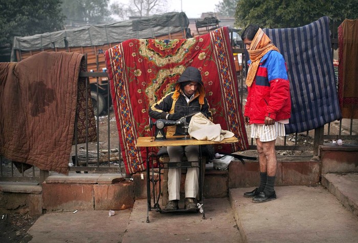 Một khách hàng đứng chờ sửa quần ven đường tại New Delhi, Ấn Độ ngày 19/1