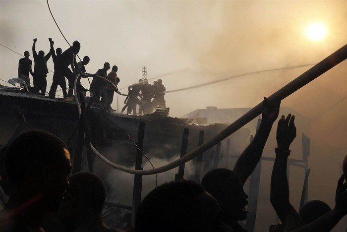 Người dân địa phương phối hợp với lực lượng cứu hỏa dập tắt đám cháy thiêu rụi hàng chục ngôi nhà tại khu ổ chuột ở trung tâm Malabo, Guinea hôm 23/1