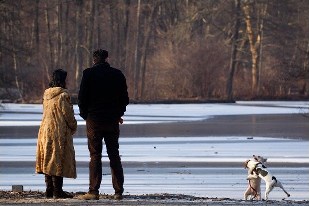 NMột cặp đôi đứng ngắm những chú chó đùa giỡn tại hồ đã đóng băng ở công viên Tiergarten, Berlin trong một ngày đông lạnh lẽo.