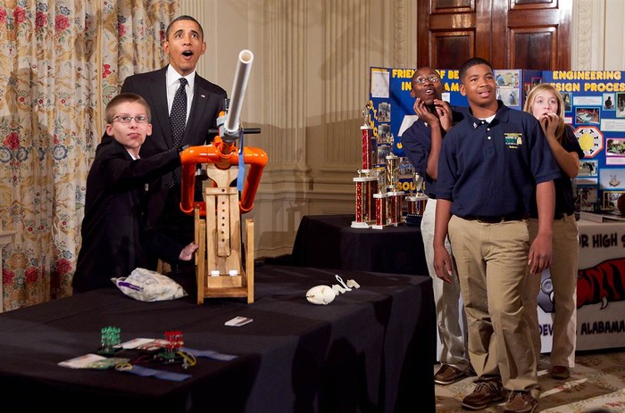 Tổng thống Obama xem cậu bé Joey Hudy (14 tuổi) sử dụng cỗ máy tự chế tạo tại Hội chợ khoa học Extreme Marshmallow Cannon diễn ra ở Nhà Trắng hôm 7/2 vừa qua. Đây là hội chợ lần thứ 2 do Tổng thổng Mỹ tổ chức dành cho đối tượng học sinh trung học.