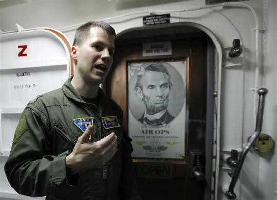 Trung úy Matt Driskill đứng cạnh bức ảnh của tổng thống Abraham Lincoln trên tàu USS Abraham Lincoln ngày 14/2/2012