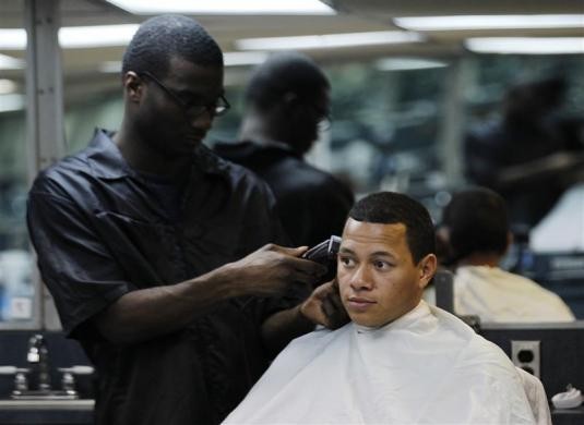 Kỹ thuật viên Điện tử Hàng không Calvin Dean (phải) cắt tóc tại phòng cắt tóc trên tàu sân bay hôm 14/2/2012