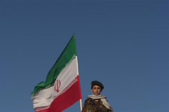 Một thành viên IRGC đứng cạnh một lá cờ Iran trong cuộc biểu tình chống Mỹ buổi tại Quảng trường Azadi ở Tehran ngày 25/4/2010.