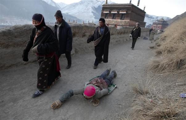 Một phụ nữ Tây Tạng quỳ xuống đất cầu nguyện gần tu viện Labrang ngày 21/2.