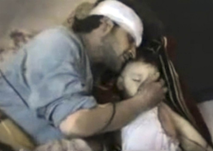 Hình ảnh này được lấy từ video nghiệp dư trên mạng Shaam News Network ngày 22/2 cho thấy một người đàn ông đang vuốt má cậu con trai nhỏ được cho là bị giết bởi lực lượng an ninh của chính phủ Syria trong trận pháo kích tại Homs 2 ngày trước đó.
