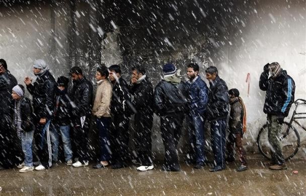 Những người đàn ông xếp hàng đợi mua bánh mỳ tại một tiệm bánh trong mùa đông ở Al Qusayr, thành phố miền tây cách Homs khoảng 4,8 km ngày 1/3.