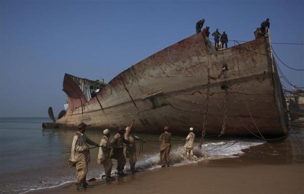 Các công nhân đang cố kéo sợi xích sắt để bóc tách con tàu cũ lấy kim loại phế liệu tại cảng Gaddani, cách Karachi, Pakistan khoảng 60 km.