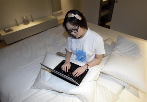 Dùng máy tính trên giường ngủ của một khách sạn tại Bắc Kinh.