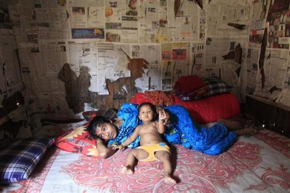 Nazma 17 tuổi nằm trong căn phòng nhỏ với cậu con trai tại nhà chứa ở Faridpur, miền trung Bangladesh ngày 23/2/2012.