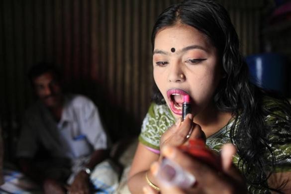 Maya (16 tuổi) tô lại son môi sau khi tiếp khách trong căn phòng nhỏ của mình tại nhà chứa Kandapara ngày 5/3/2012.