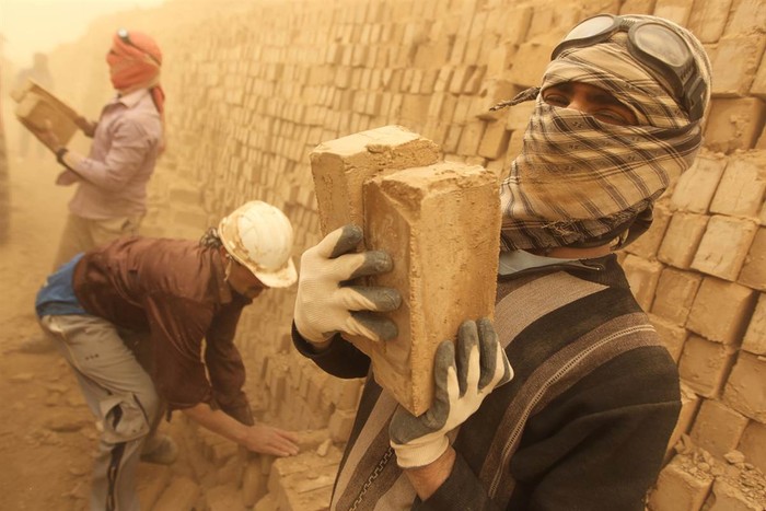 Các công nhân Iraq đang xếp những viên gạch vừa được sấy khô trong cơn bão cát tại Maysan, cách Baghdad 250 dặm về phía nam ngày 18/3.