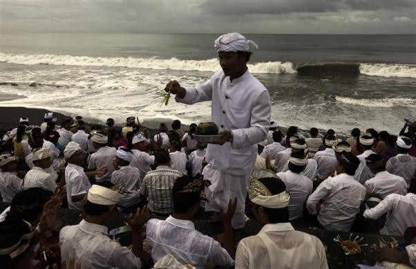 Một thầy tu Hindu vảy nước thánh cho các tín hữu tham gia nghi lễ Melasti tại bãi biển Lebih ở huyện Gianyar, Bali ngày 21/3