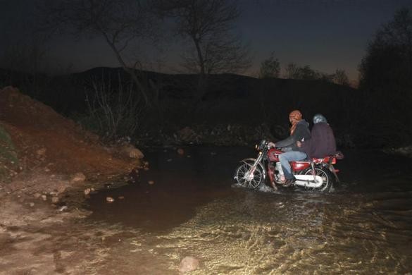 Hai người Syria đi xe máy qua sông tới làng Wadi Khaled gần biên giới với Lebanon trên đường bỏ chạy khỏi thành phố Homs ngày 21/3/2012.